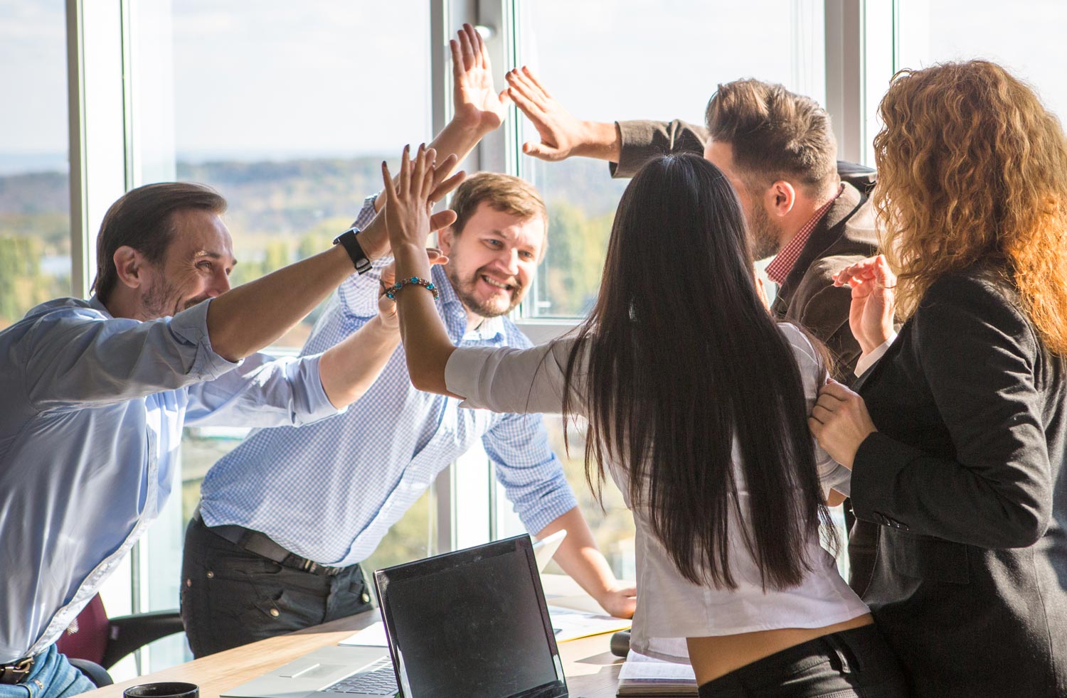 group of co-workers high fiving in the office