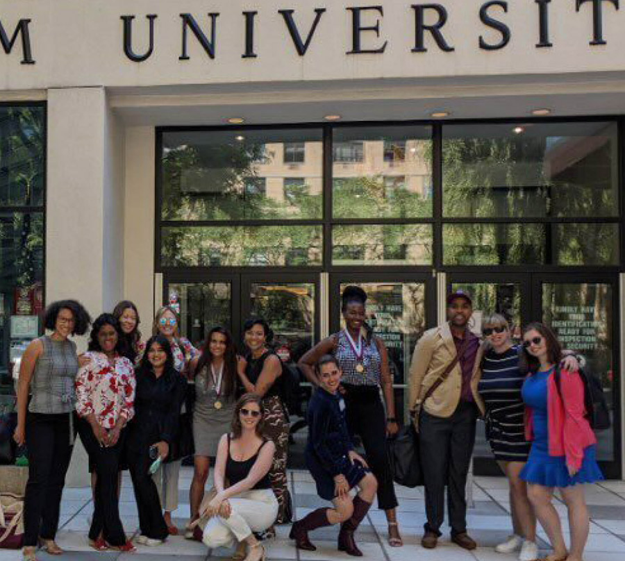 group of students and faculty in front of a University sign