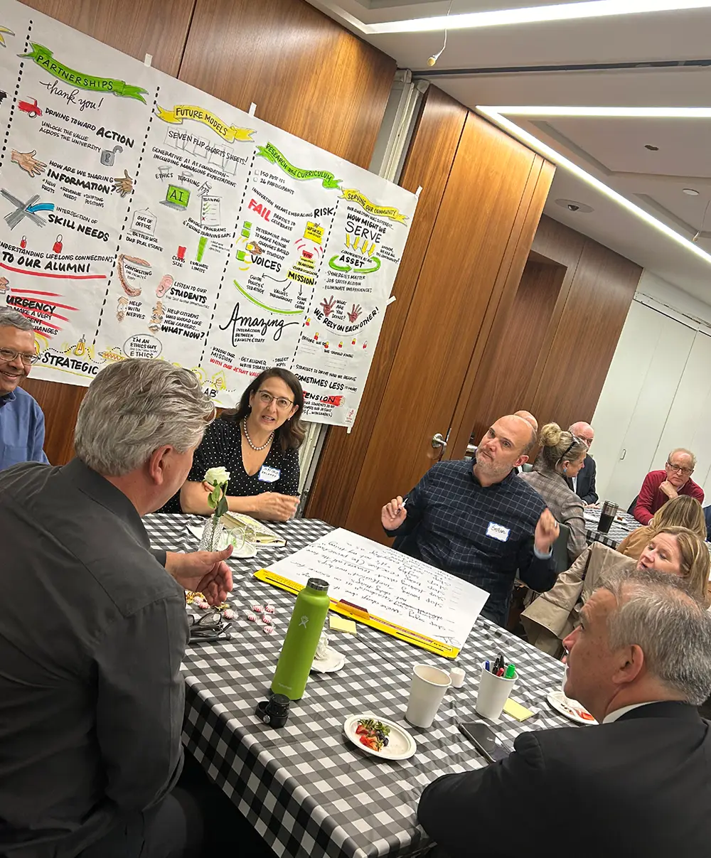 People engaged in discussion around a table with posters on the wall.