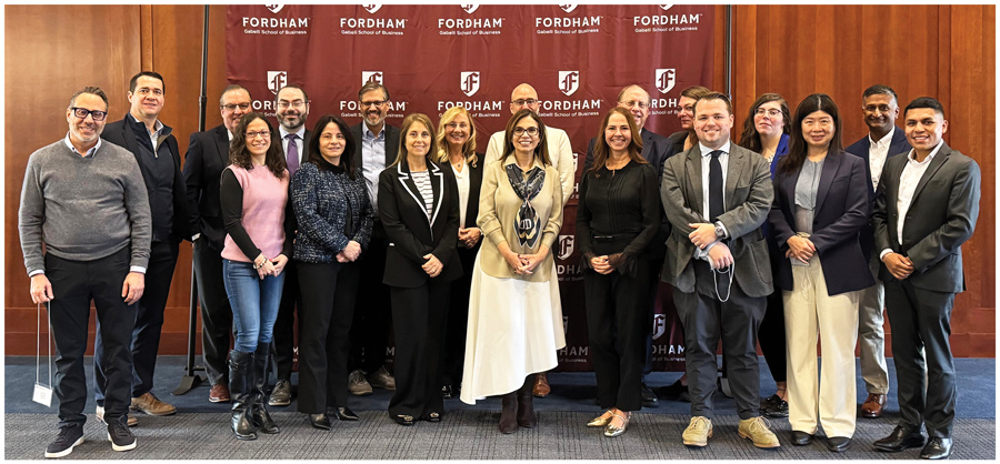 A large group of professionals poses for a photo in front of a Fordham backdrop.