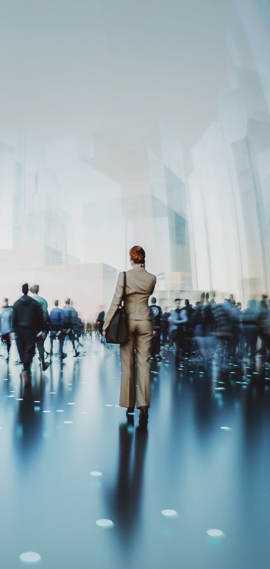 Rear view of a woman in a tan suit walking through a blurred crowd in a modern, brightly lit office lobby.